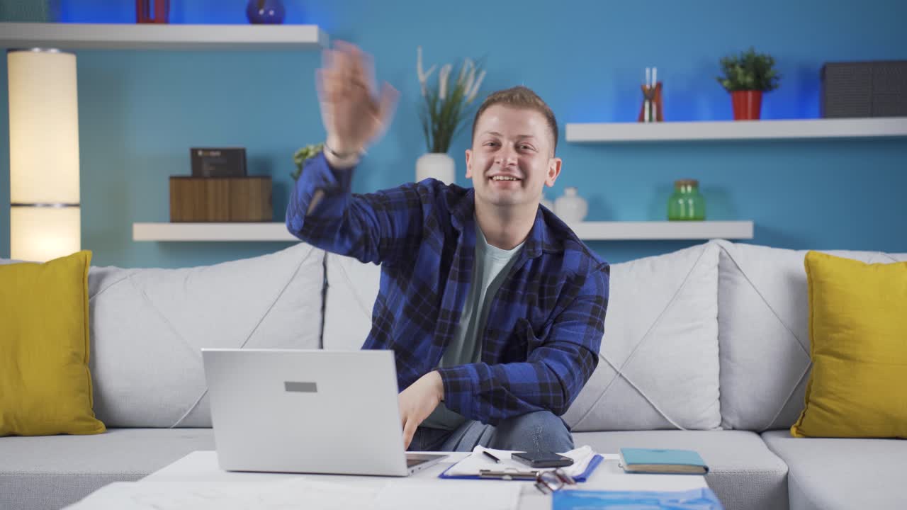 홈 오피스 워커가 카메라를 향해 손을 흔들고 있습니다.