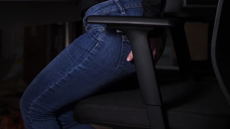 woman wants to sit on a chair and feels sudden anal pain, jumps up and sits slowly again having hand on her buttock