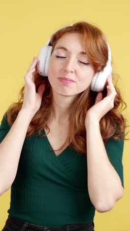 joyful redhead woman dancing and singing while listening to music with headphones
