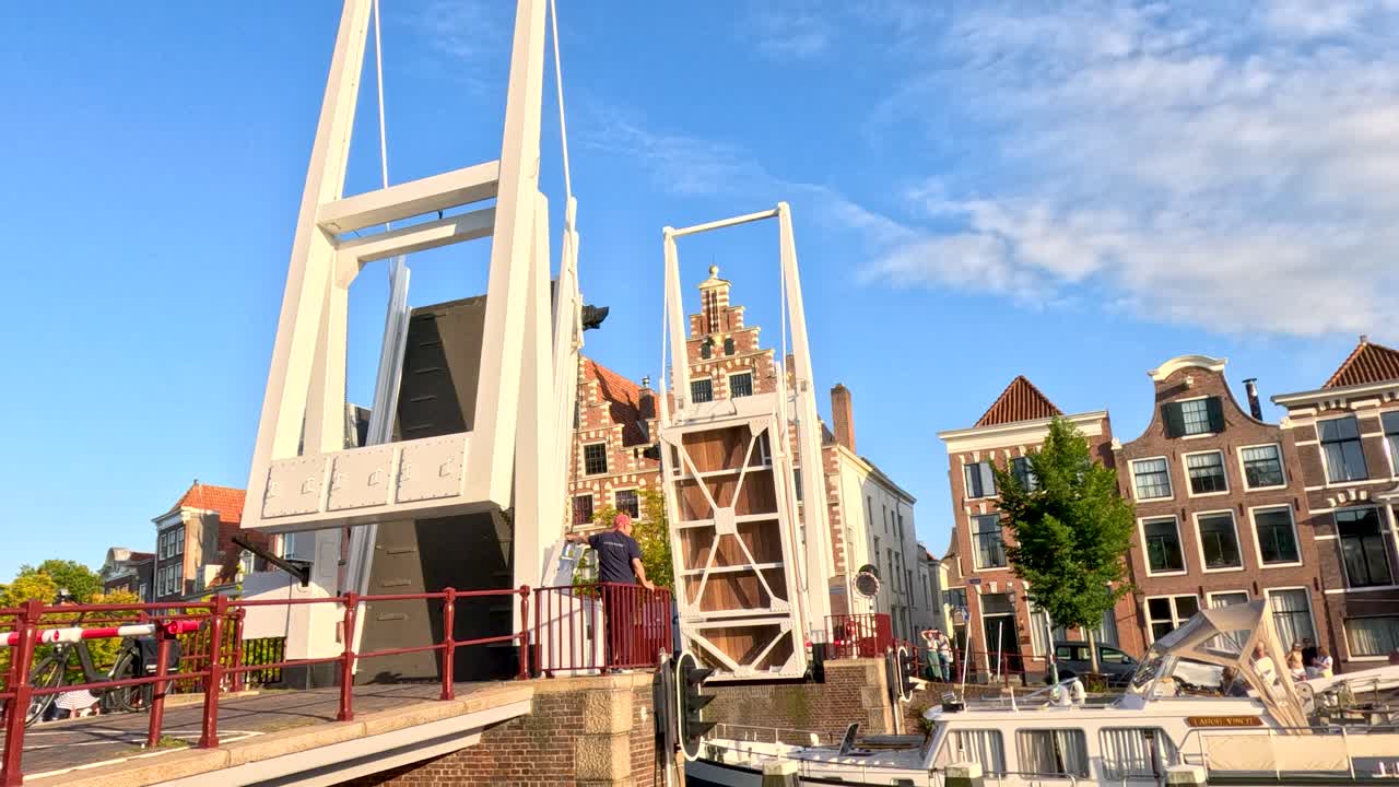 Modern drawbridge lifts for canal boats amid historic Dutch architecture, bright daylight, steady camera
