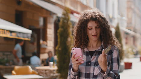 Young woman using credit bank card smartphone while transferring money purchases online shopping