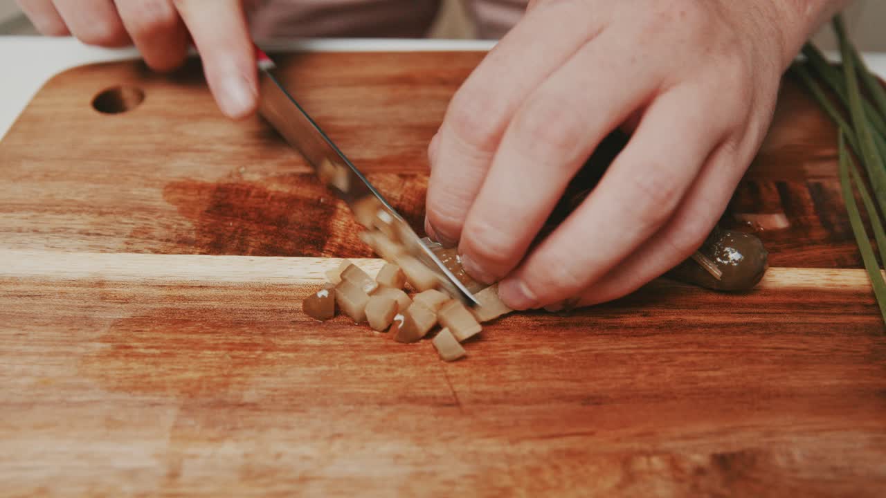 Cutting pickled cucumbers on wooden cutting board