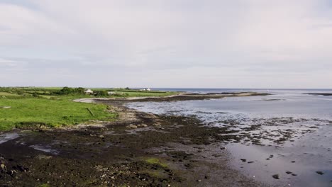 an irish coast low drone video at low tide as coastal cottages look over the scene, hd drone video