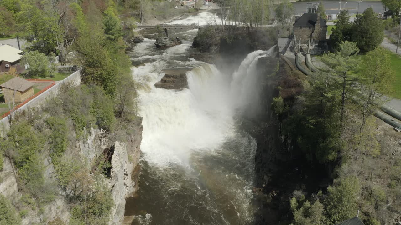 드론 샷, 천천히 뒤로 날아 작은 무지개를 생성하는 큰 폭포를 보여줍니다.