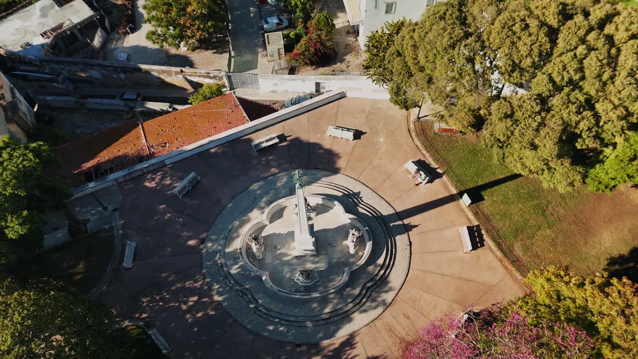 Aerial view of a town square with a monument and surrounding buildings and trees