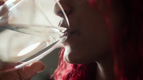 Close-up-of-cheerful-African-American-woman-drinking-glass-of-fresh-water-in-the-morning