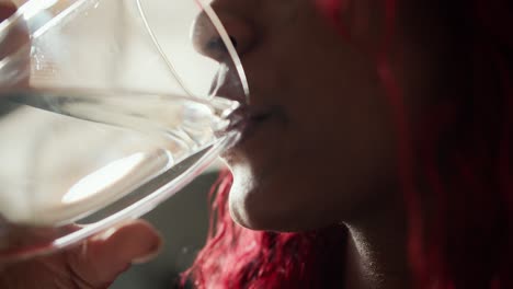 close up of cheerful african-american woman drinking glass of fresh water in the morning