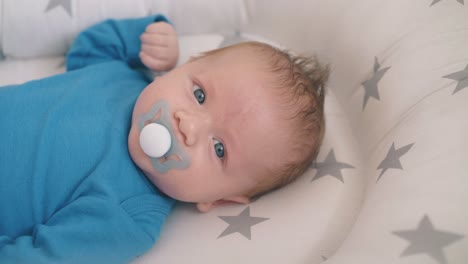 small-kid-with-pacifier-rests-in-sleeping-cocoon-closeup