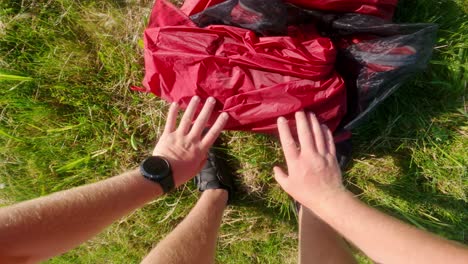 bikepacking cyclist folds a red tent in morning from a first-person perspective
