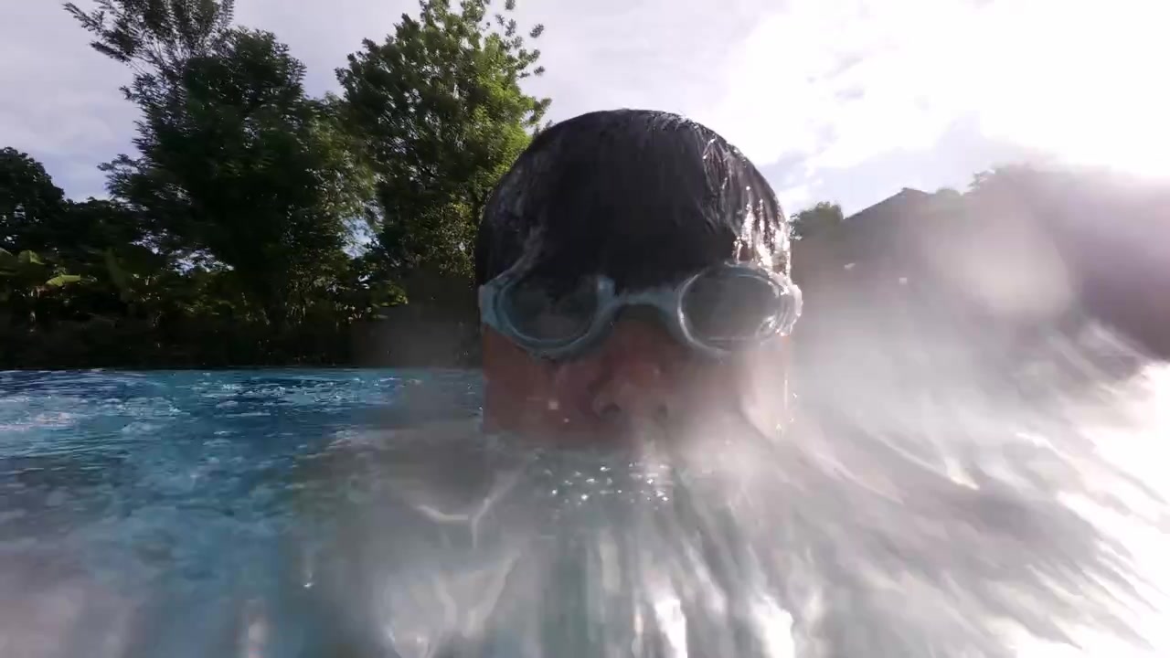 Selfie diurno in POV di un uomo che si tuffa nella piscina di una villa ed emerge dall'acqua