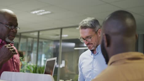 Diverse-male-business-colleagues-talking-and-using-laptop