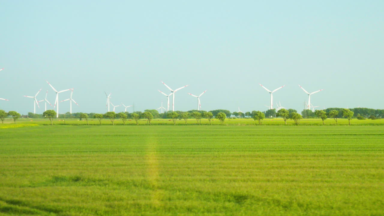풍경적 인 풍력 발전소 풍경: 파란 하늘 과 초록색  ⁇  씨 ⁇  들 사이 에 있는 풍력 터빈