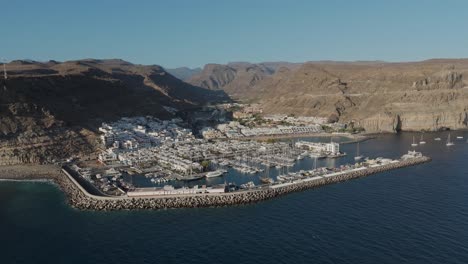 Drone-view-of-the-picturesque-fishing-village-Puerto-de-Mogan,-a-harbourside-European-town-with-a-beautiful-beach,-Spain