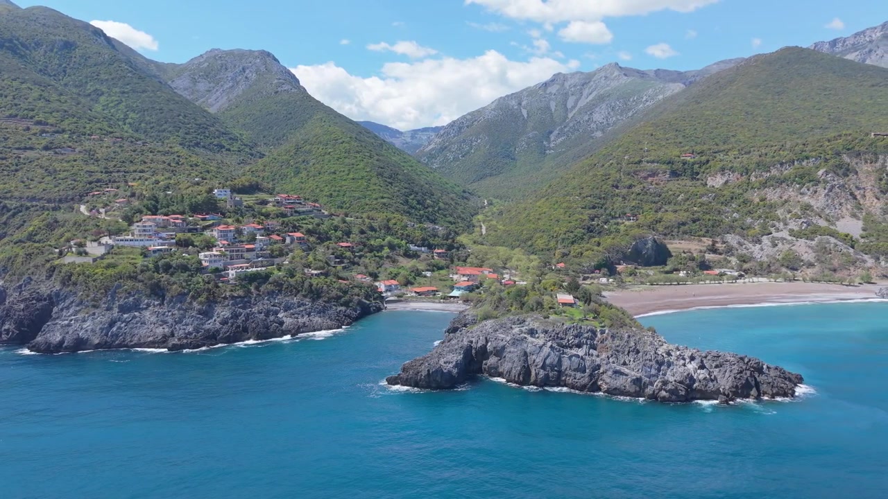 Filmagem de drone capturando a espetacular beleza natural da Praia de Limnionas, revelando águas turquesa, terreno acidentado e paisagem mediterrânea exuberante sob céus azuis claros.