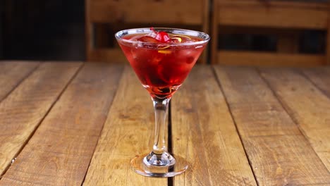 waiter dropping a cherry into a red fruit cocktail