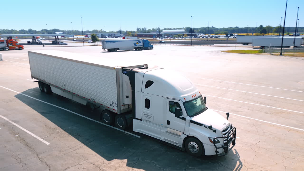 Chicago, USA, 29 June 2025: Close aerial view of a white semi truck parked near a highway exit with road and green fields in the background