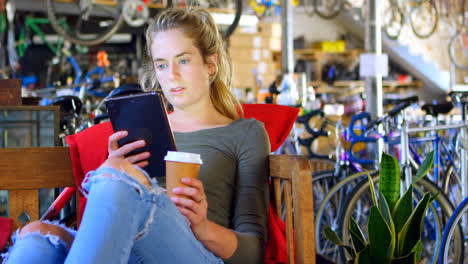 woman having cold coffee while using digital tablet at workshop 4k