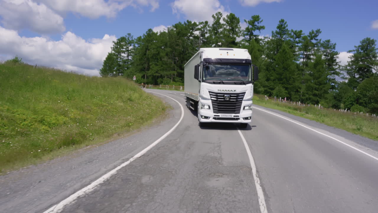 Hvid KamAZ lastbil på en snoet bjergvej