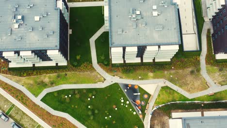 drone overhead push down shot of area in the middle of a residential building with cars, children's playground and parking for cars in the house courtyard