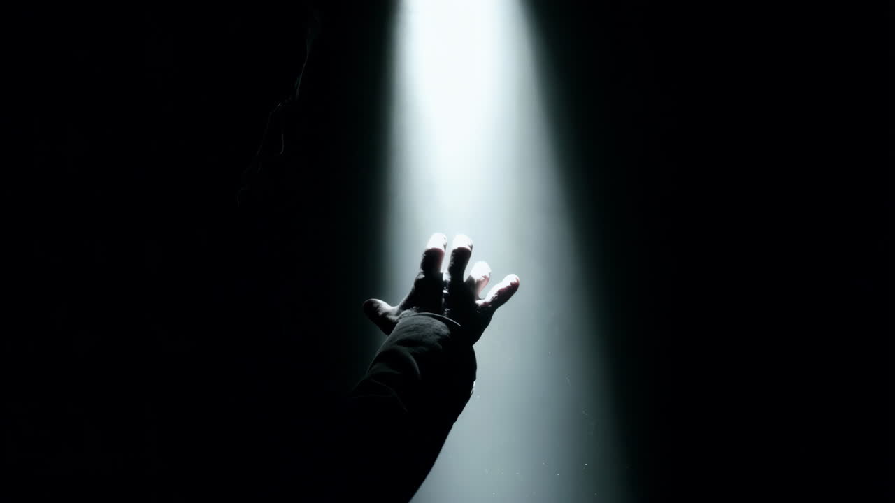 Hand Reaching for Light in Darkness