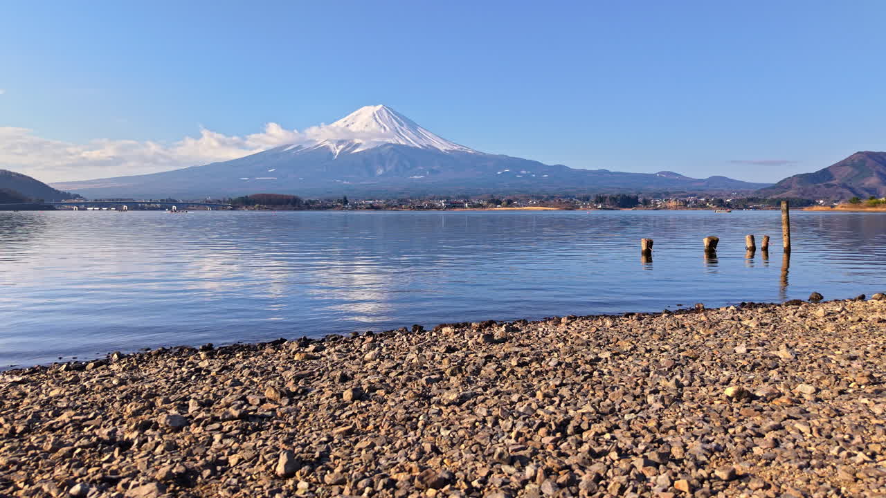 Aerial drone view of a shore with stones and Lake Kawaguchiko in Japan with Mount Fuji on the background in daylight