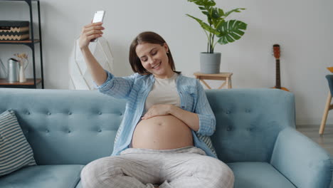 pregnant woman taking a selfie on the sofa