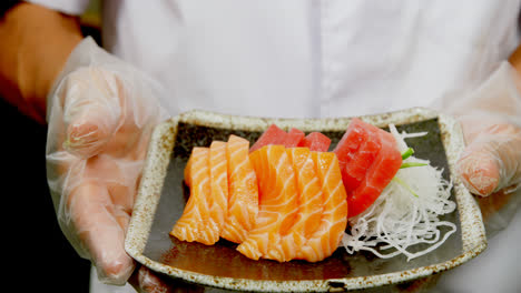 male chef holding a plate with sushi in kitchen 4k