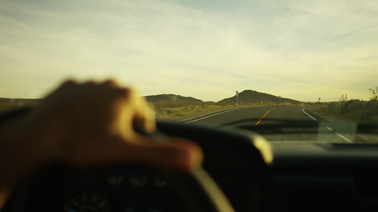 Girl driving desert road at sunset