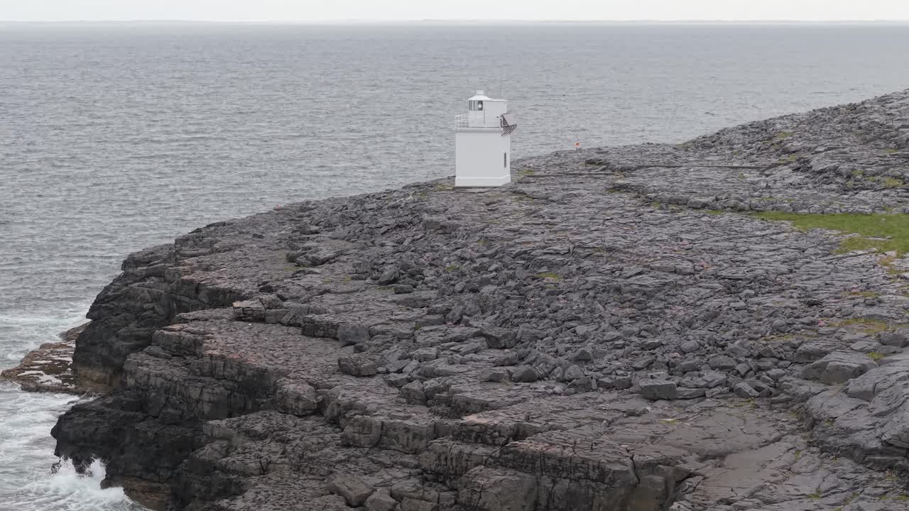 A solitary lighthouse stands atop rugged rock formations along Ireland's west coast, near The Burren