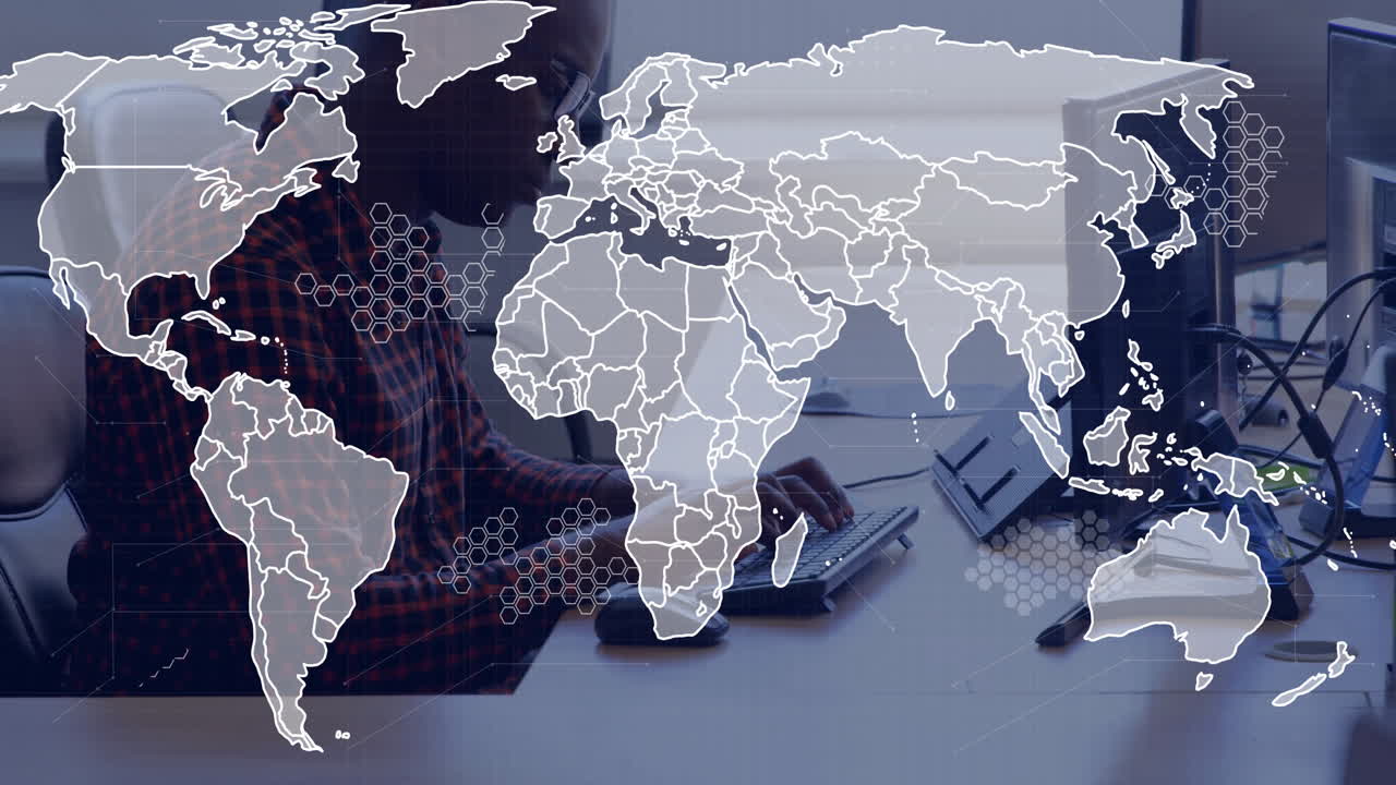 Software developer typing at keyboard in modern office, overlaying global map with hexagon data