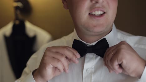 groom man adjusts bow tie, preparing to go to the bride, businessman in white shirt, wedding day