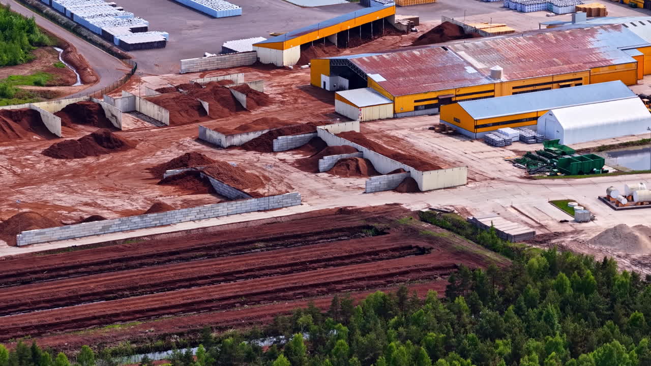 Peat factory yard with large open peat piles, processing structures and storage areas