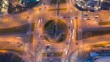 top-down nighttime view at a huge roundabout in warsaw, poland. lots of traffic, pedestrians.
