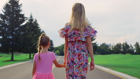 vista trasera de una mujer y una niña caminando al aire libre