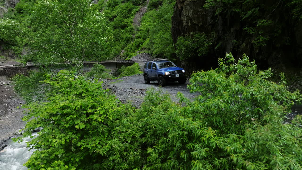 Veicolo fuoristrada blu in transito sul passo di montagna all'interno del Parco Nazionale di Tusheti, Georgia.