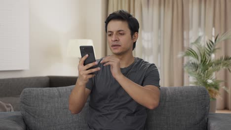 Tired-Indian-man-scrolling-phone