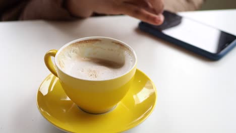 mujer usando el teléfono mientras bebe café