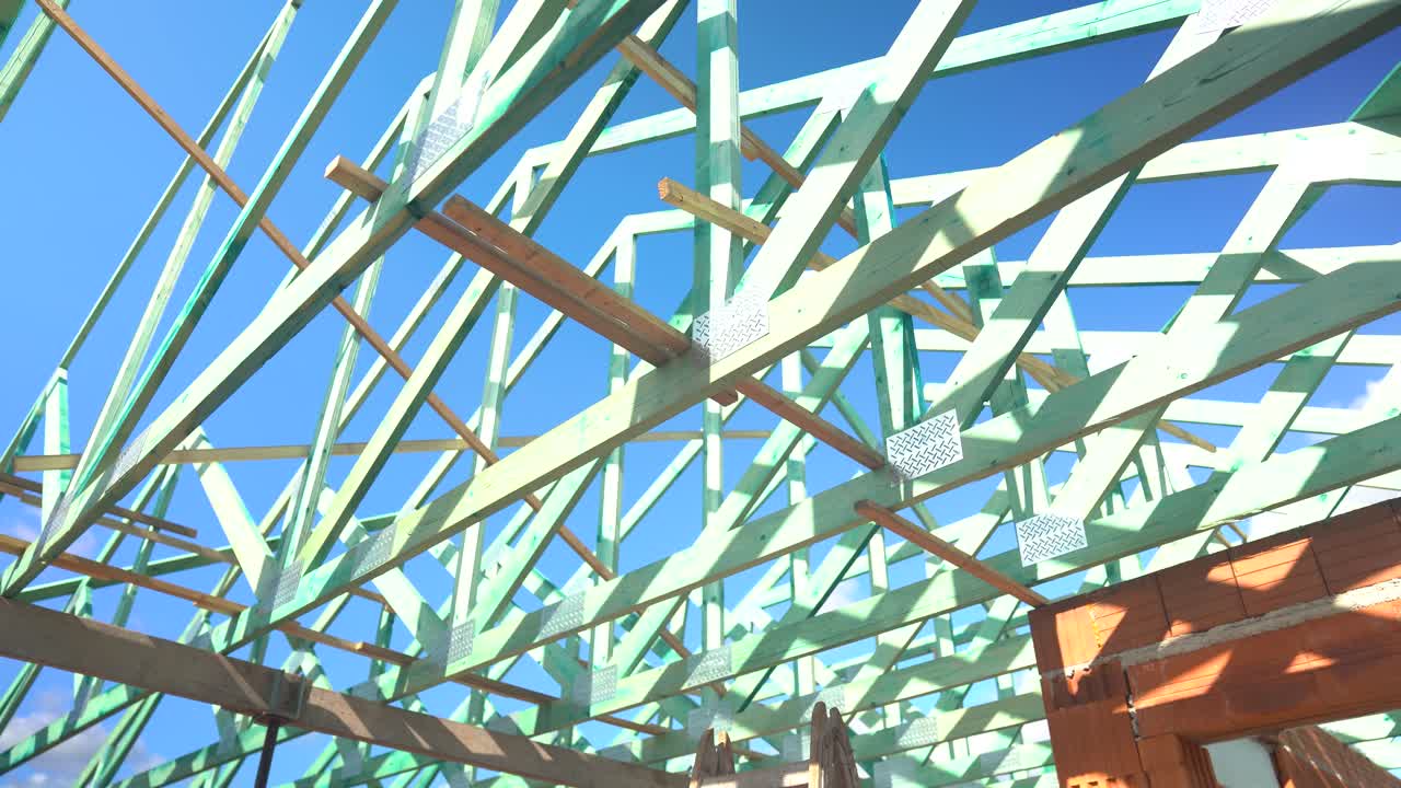 Interior view of timber roof truss framing against blue sky on construction site