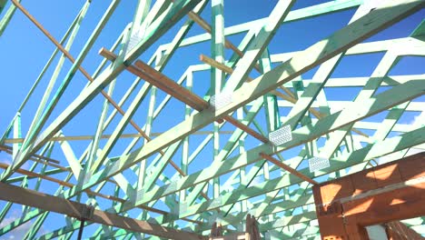 interior view of timber roof truss framing against blue sky on construction site