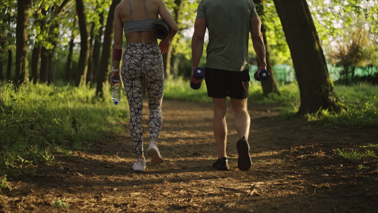 Couple exercising with weights and yoga mat in the park