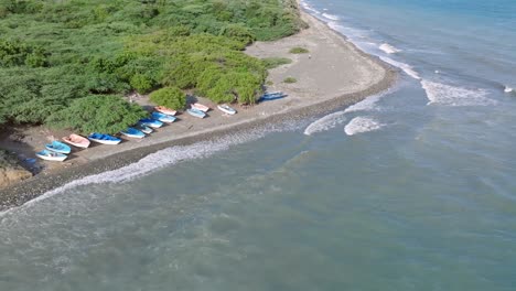 empty rural stone beach with stranded blue wooden boats, aerial orbit