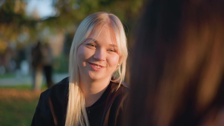 Giovane donna bionda che conversa all'aperto al tramonto
