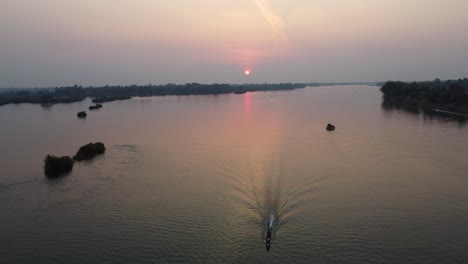 un pescador en el poderoso río mekong en el sur de laos, haciendo su camino a casa antes de la puesta del sol