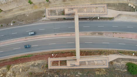 puente peatonal a pie sobre una calzada concurrida con coches circulando por debajo