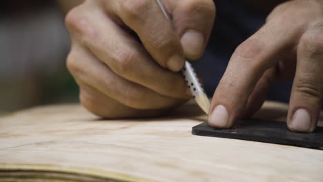 handen van vakman die de locatie van de wielen op skateboard markeert met potlood, bewegingsweergave