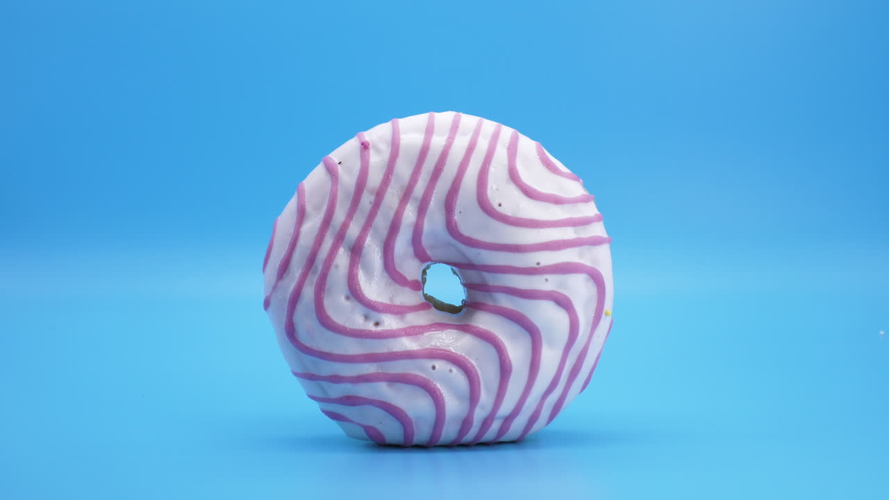 대비되는 파란색 배경에 분홍색 소용돌이가 있는 아이스 도넛