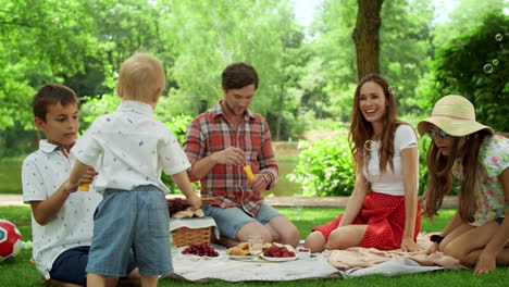 family having fun together in park. siblings playing with soap bubbles in forest