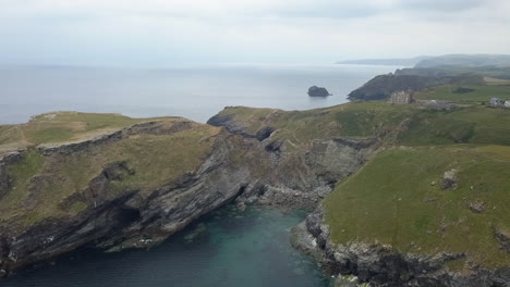 Misty-Cornwall-coast-aerial-to-King-Arthur's-Camelot-Castle-ruin