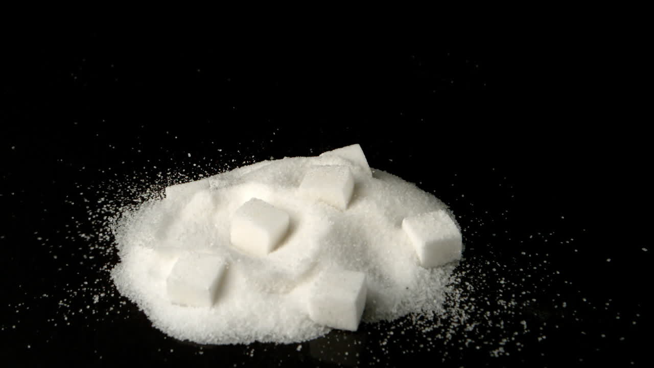 cubo de azúcar cayendo en una pila de azúcar en polvo