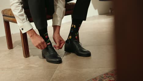 a man tying laces on black leather shoes